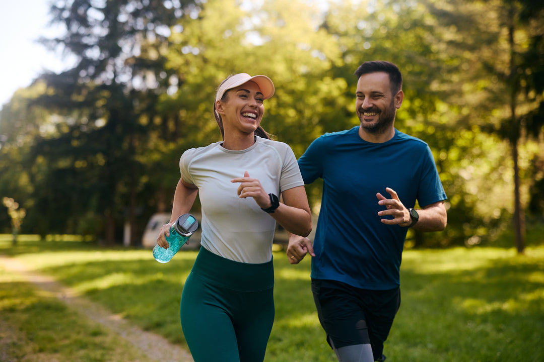 Junge Frau und junger Mann joggen im Wald und sehen glücklich aus